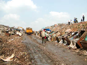 ゴミ山に続く道路は収集車とゴミを拾う男たちでにぎわいを見せている